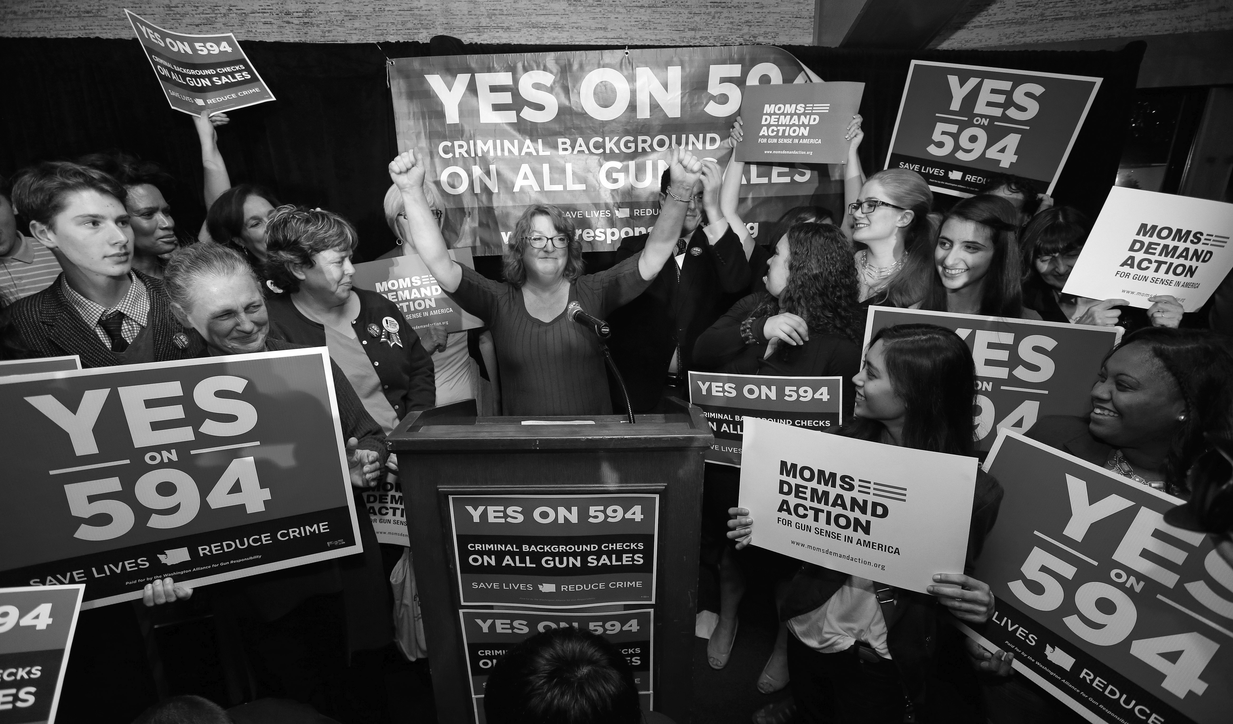 Cheryl Stumbo, center, raises her arms as she finishes speaking at an election night party for Initiative 594, a measure seeking universal background checks on gun sales and transfers, Tuesday, Nov. 4, 2014, in Seattle. Stumbo, the citizen sponsor of the initiative, is a survivor in the shooting at the Jewish Federation in Seattle in 2006. The initiative is one of two competing gun initiatives in Washington state. The other measure, Initiative 591, would prevent any such expansion of background checks. (AP Photo/Elaine Thompson)